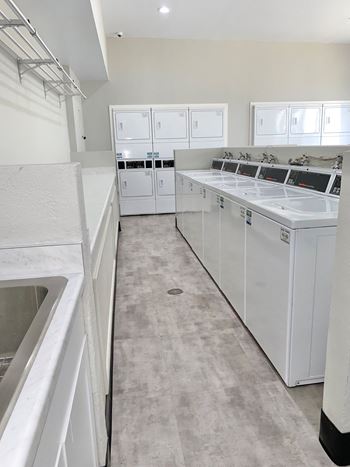 a large laundry room with white cabinets and appliances at Ascent on Pantano Apartments, Tucson, Arizona